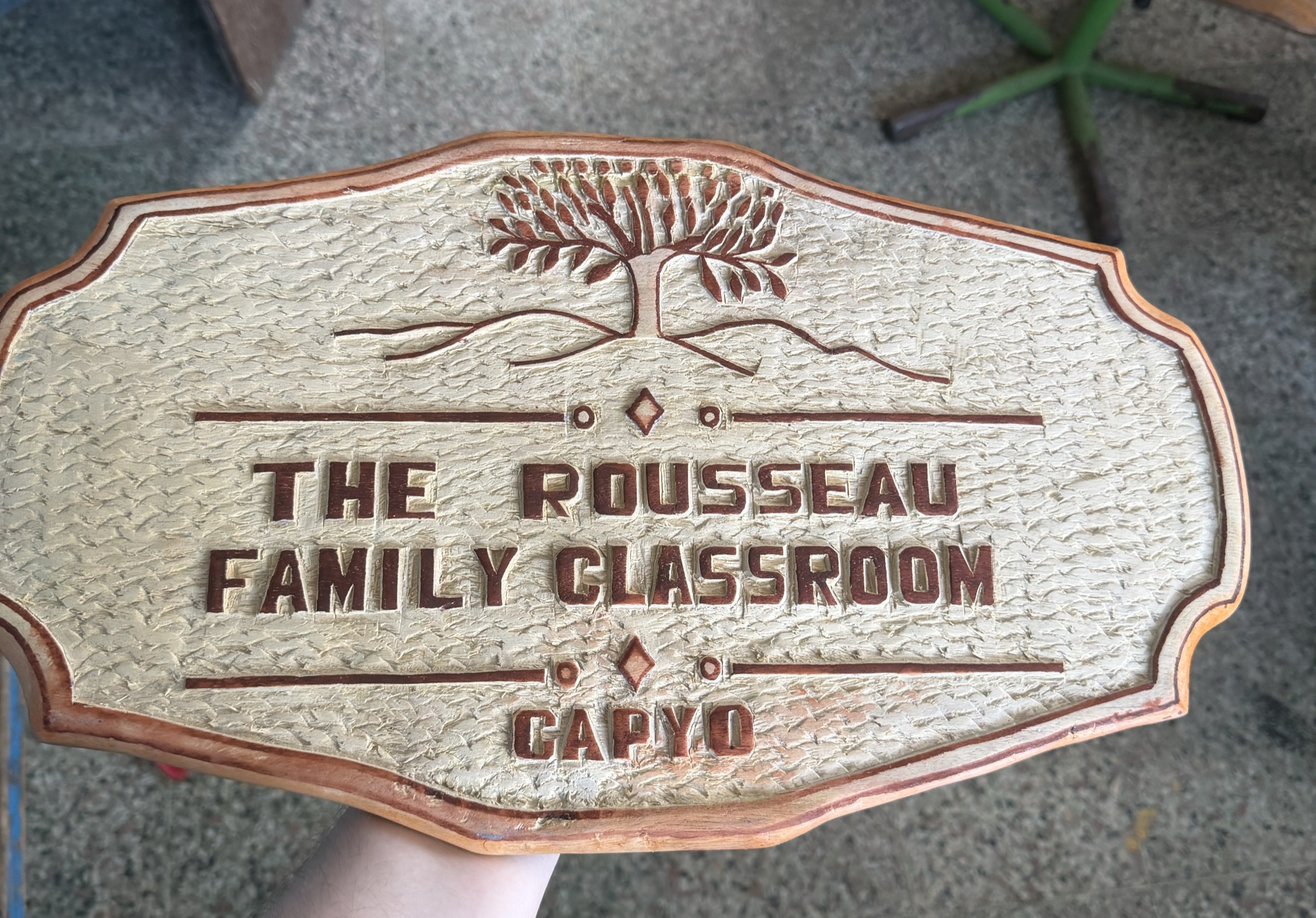 A carved wooden sign reading The Rousseau Family Classroom, Capyo